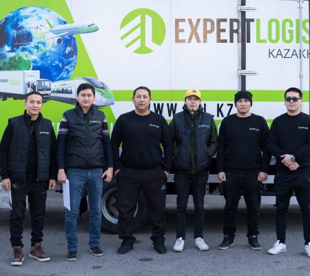 Команда Expert Logistic на фоне грузового транспорта